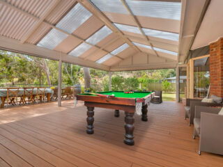 Massive decking with shaded by a gable structure and a pool table in the middle